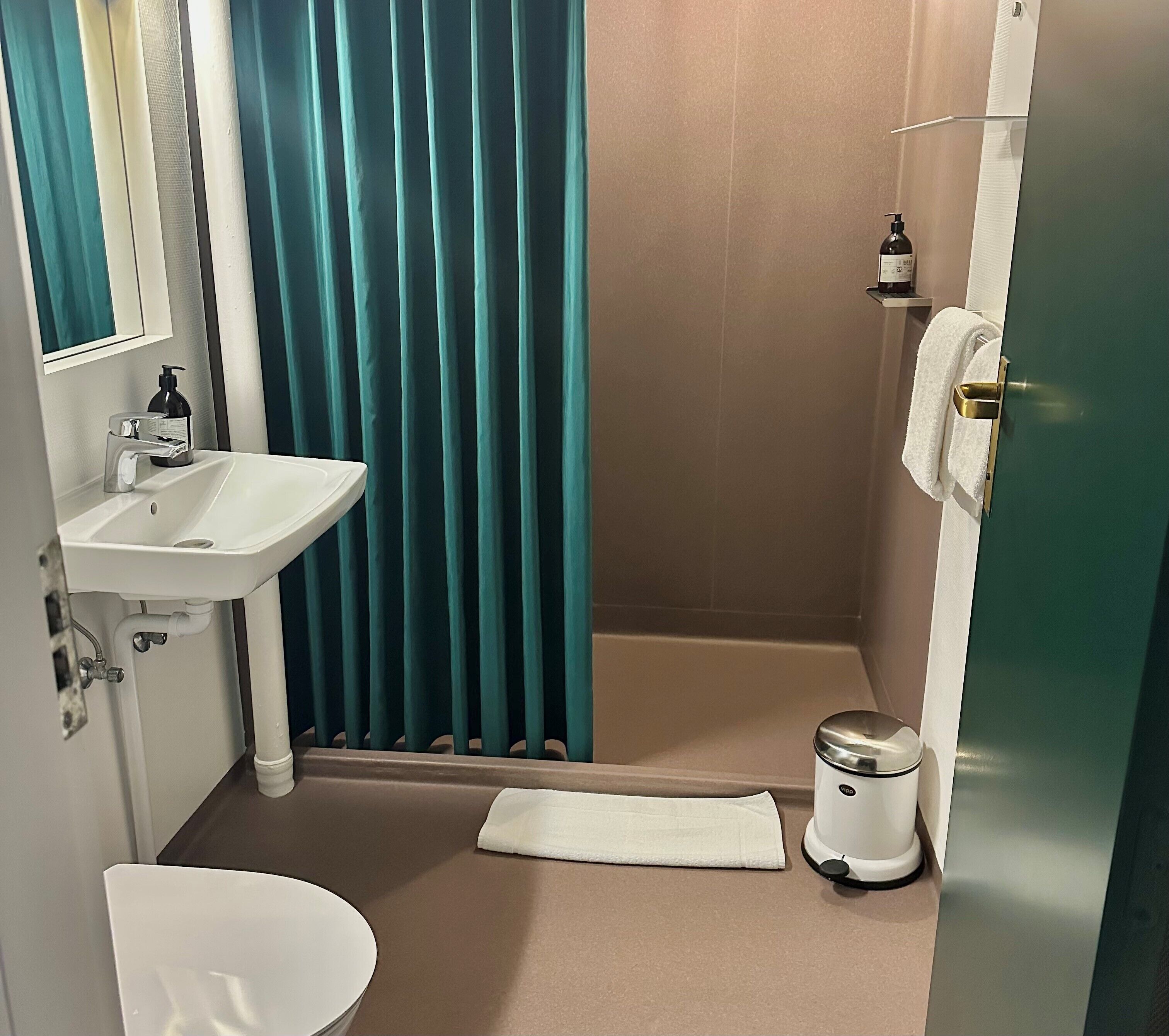 A bathroom with a sink, mirror, shower, and toilet.