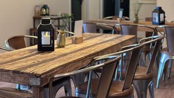 Un espace repas avec une table en bois rustique, des chaises en métal et des luminaires suspendus.