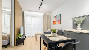 A modern living room with a dining area, large windows, and a view of the city.