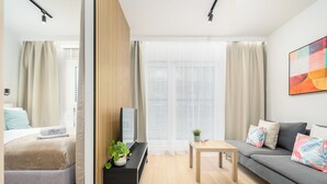 A modern hotel room with a bed, a sofa, a small table, and a bench.