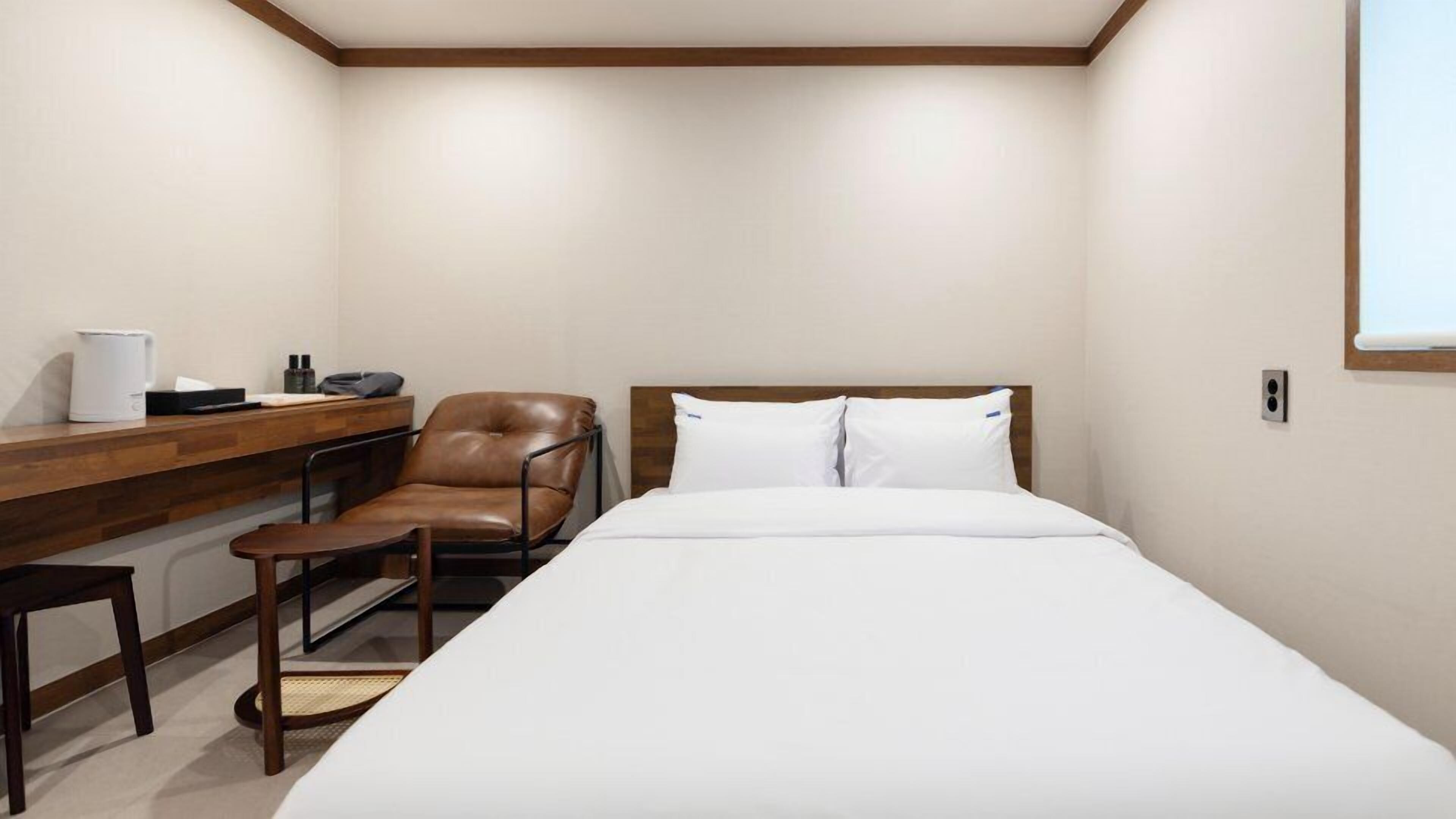 A hotel room with a bed, a desk, a chair, and a coffee maker.