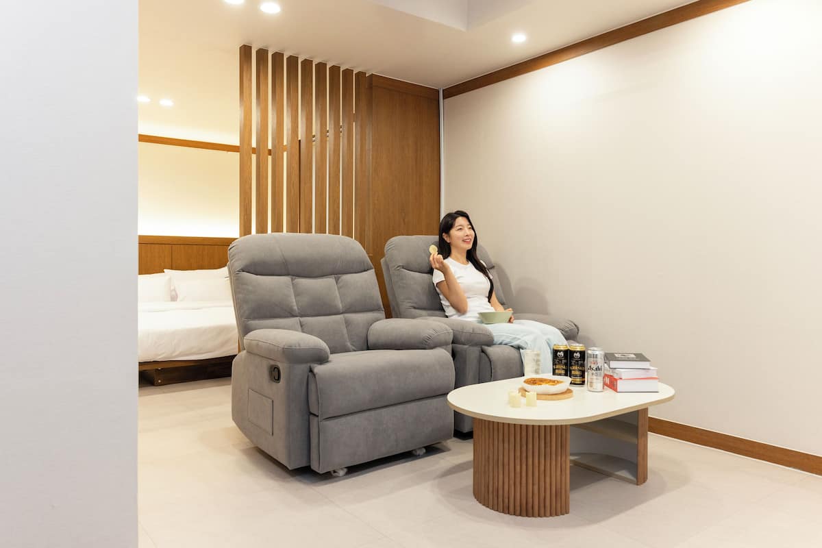 Un salon moderne avec un canapé, une table basse et un lit en arrière-plan.