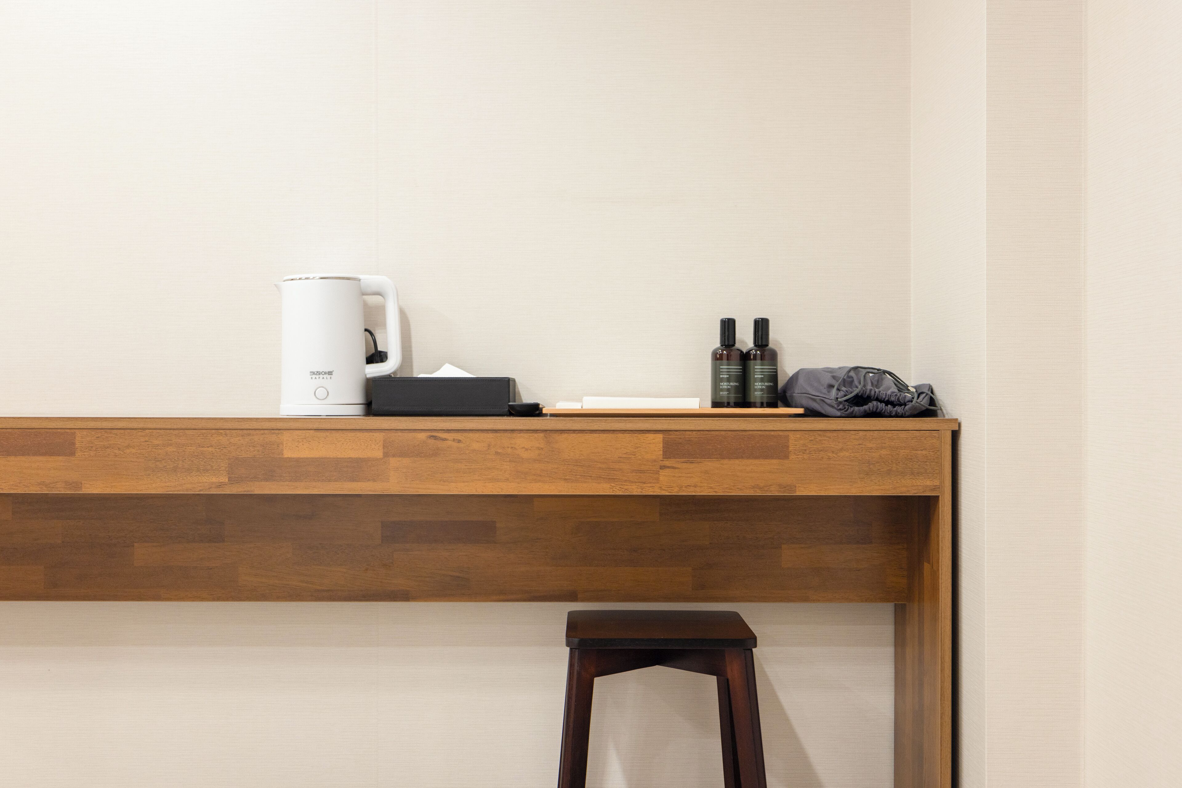 A wooden desk with a coffee maker, a tissue box, and two bottles of hand sanitizer.