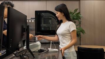 Een vrouw bedient een beeldscherm en een printer in een modern kantoor.