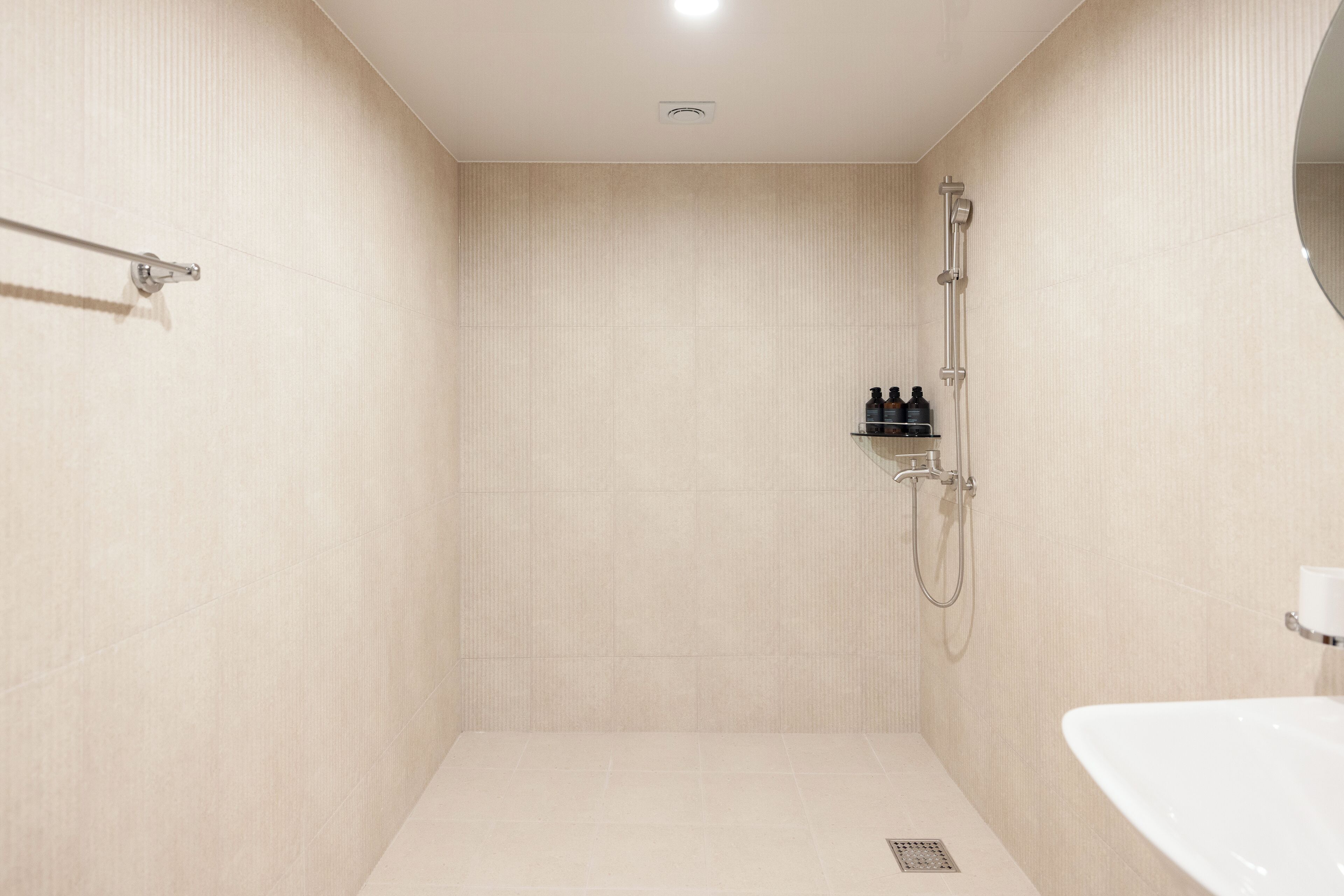 Ein modernes Badezimmer mit barrierefreier Dusche, Toilettenpapierhalter und Waschbecken.
