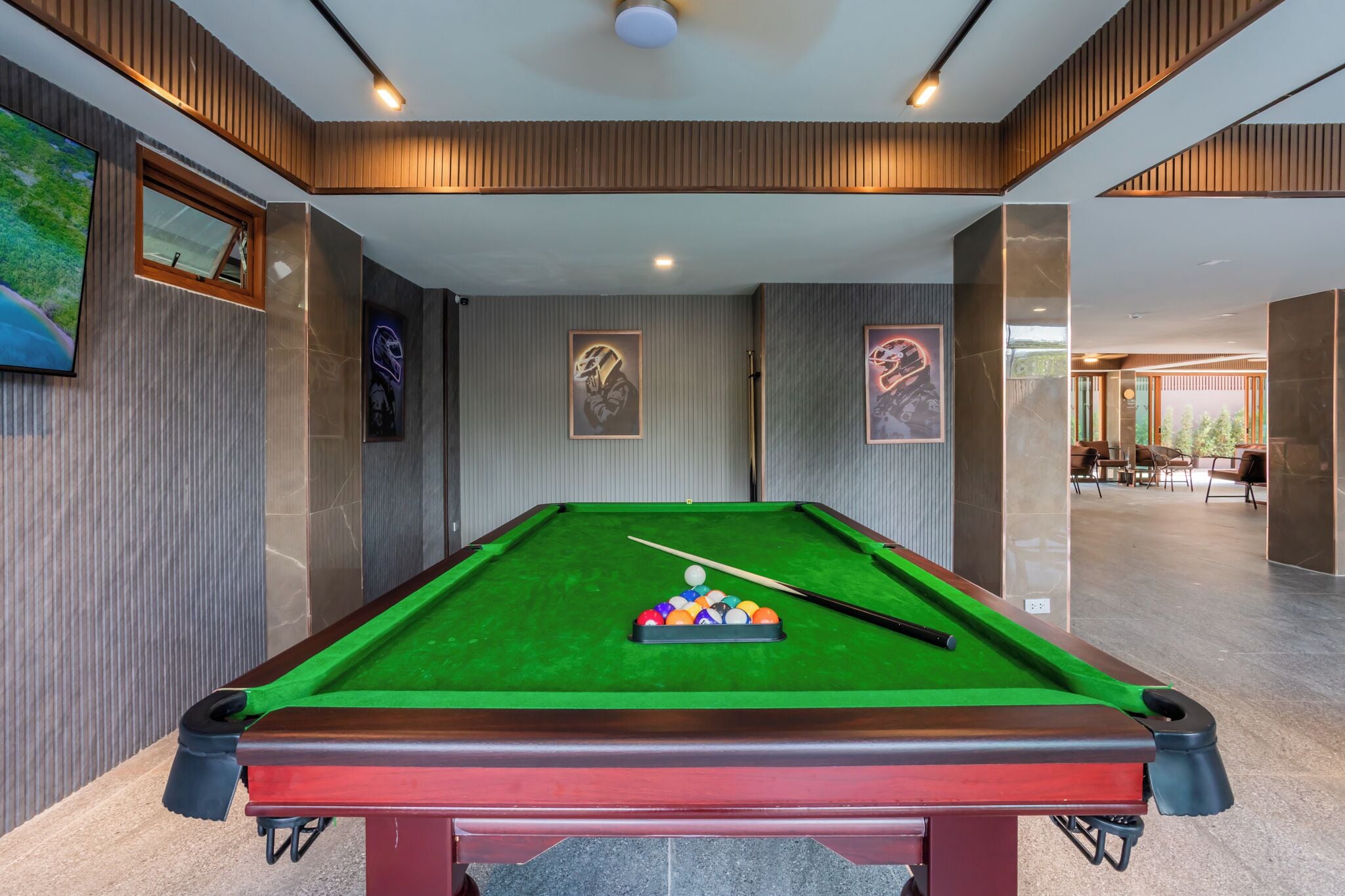A pool table with balls, wooden paneling, and framed pictures on the walls.