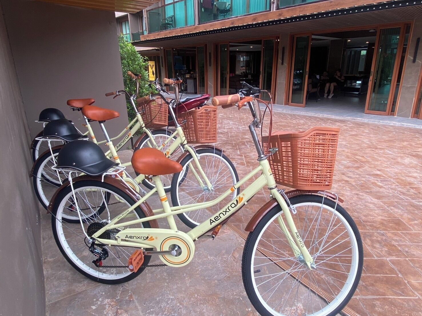 A bicycle with a basket and a seat, parked on a tiled surface.