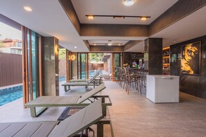 A modern indoor pool area with lounge chairs, a bar, and a view of the outdoor pool. - The Legacy V Ao Nang Beach Krabi, an Aspira collection (Krabi)
