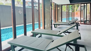 Un área moderna junto a la piscina con sillones de descanso y una pileta.