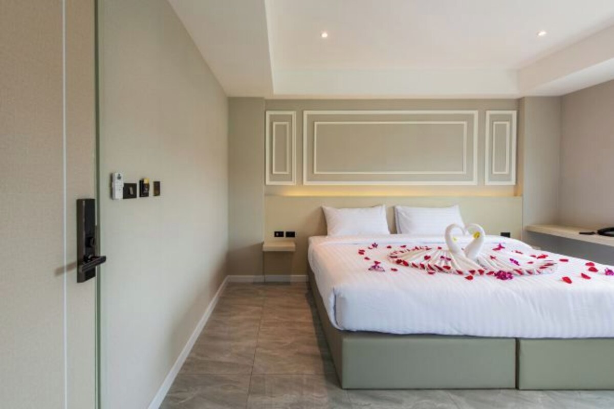 Une chambre d’hôtel avec un grand lit, une table de chevet, une lampe fixée au mur et une porte avec une poignée.