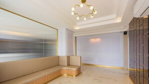 A modern interior with a curved seating area, a large mirror, and a decorative ceiling light. - THE MOMENT (Khlong Luang)