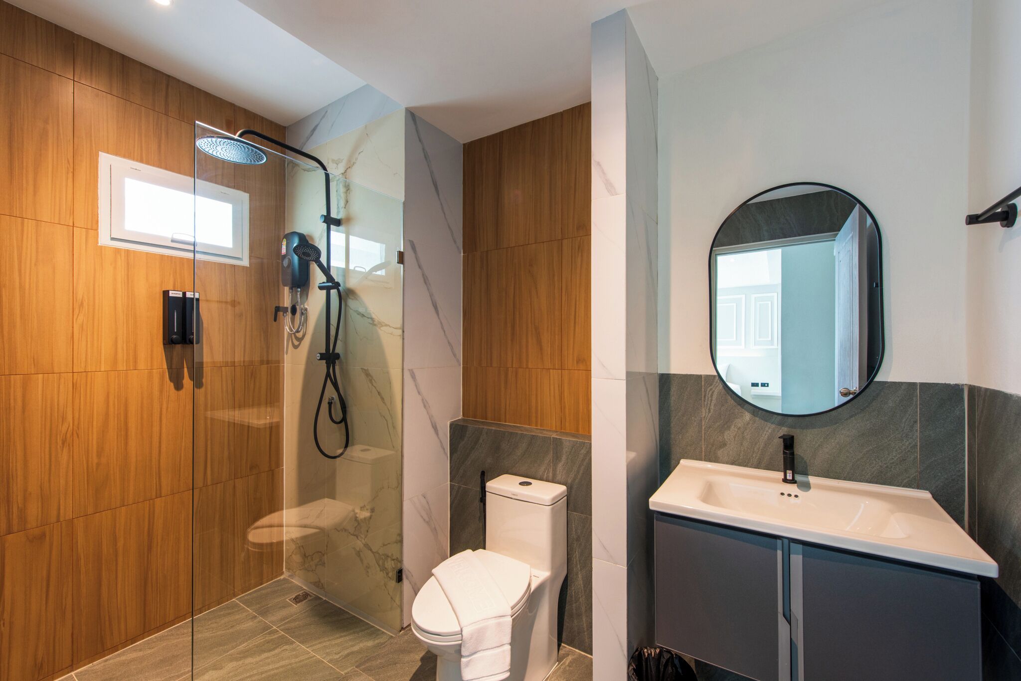 A modern bathroom with a glass-enclosed shower, a toilet, and a sink with a mirror.