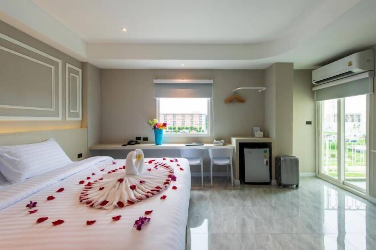 Una habitación de hotel con cama, escritorio, silla, radiador y ventana.