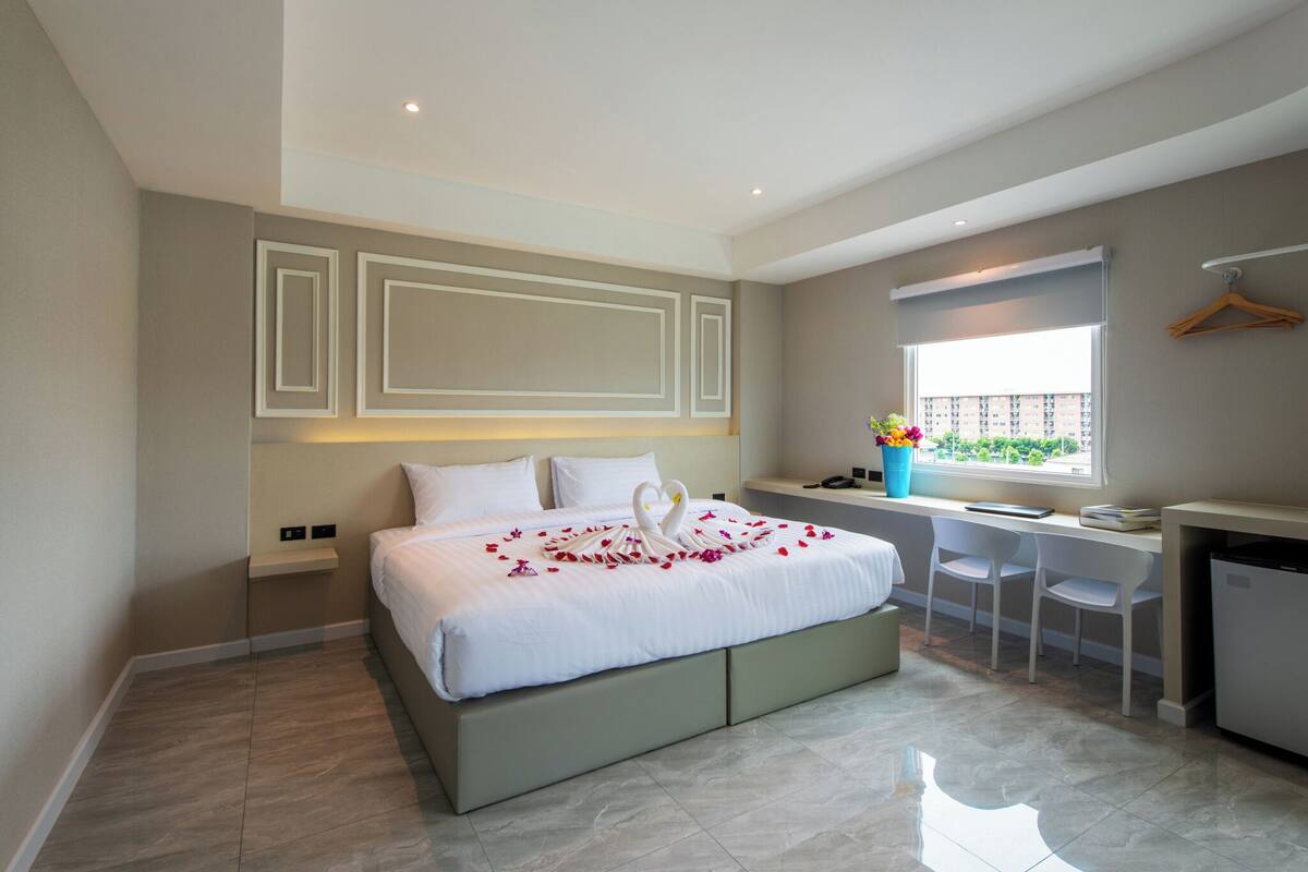 Un dormitorio moderno con cama, escritorio y ventana.