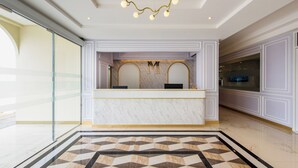 A hotel reception area with a marble counter, a geometric patterned floor, and a chandelier. - THE MOMENT (Khlong Luang)