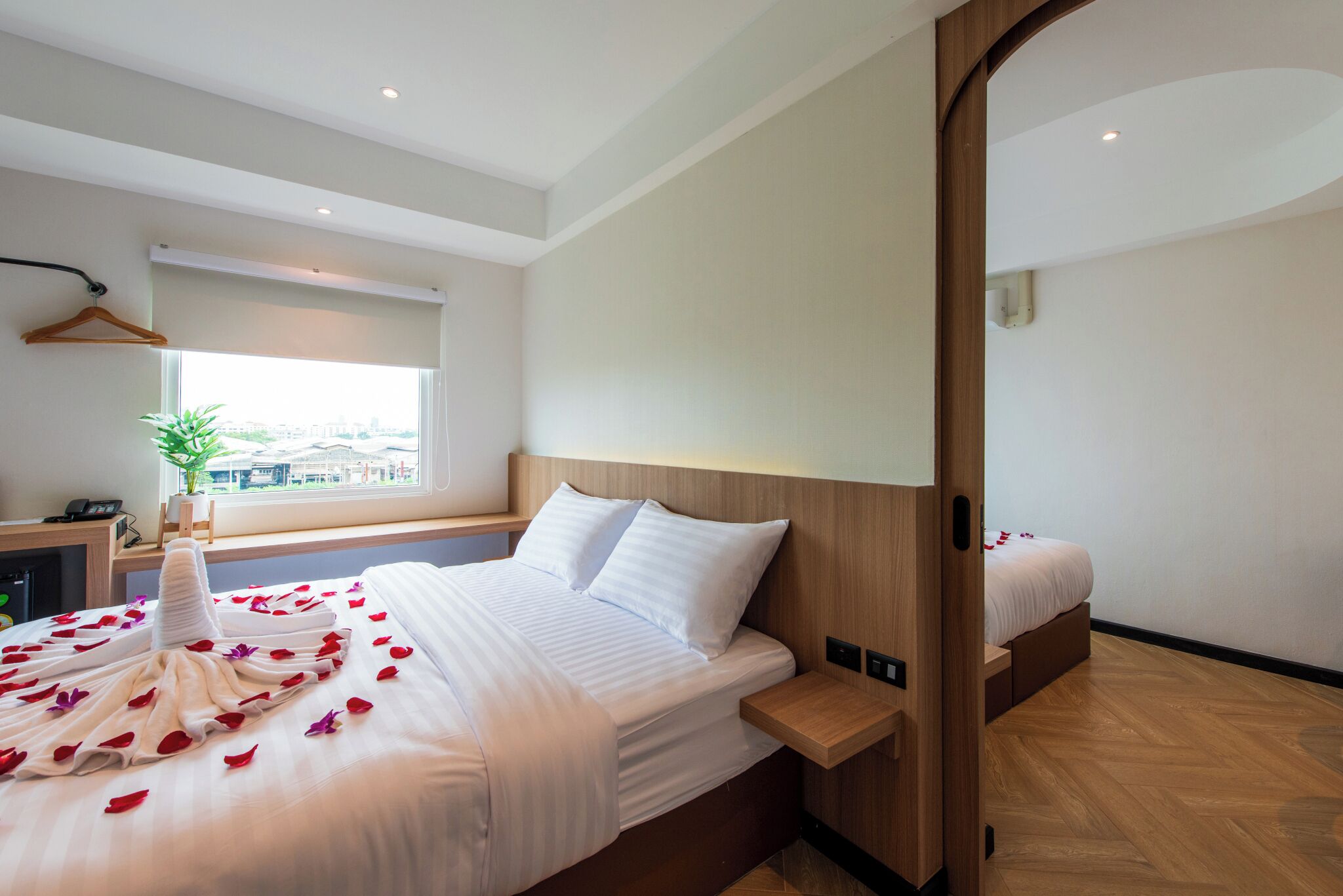 Habitación de hotel con una cama grande, una mesita de noche, una ventana con vistas y un cabecero de madera.