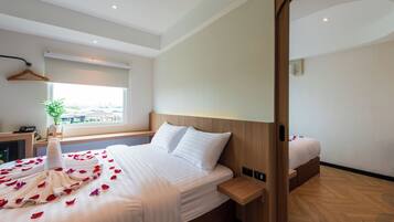 Habitación de hotel con una cama grande, una mesita de noche, una ventana con vistas y un cabecero de madera.