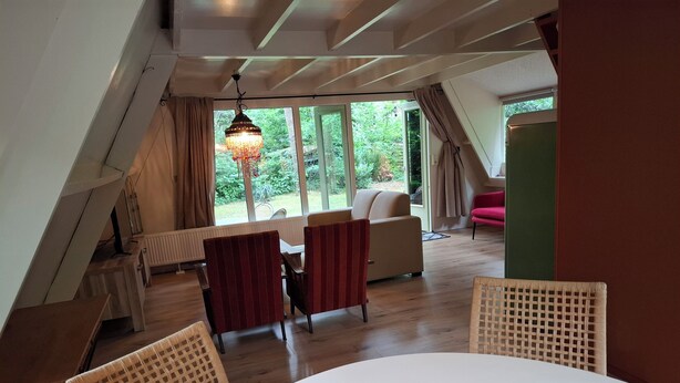 An attic room with a dining table and chairs, a sofa, and a hanging light fixture.