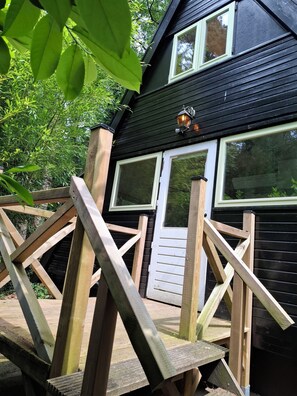 Ein schwarzes Haus mit weiß verzierten Fenstern und einer Holzterrasse.