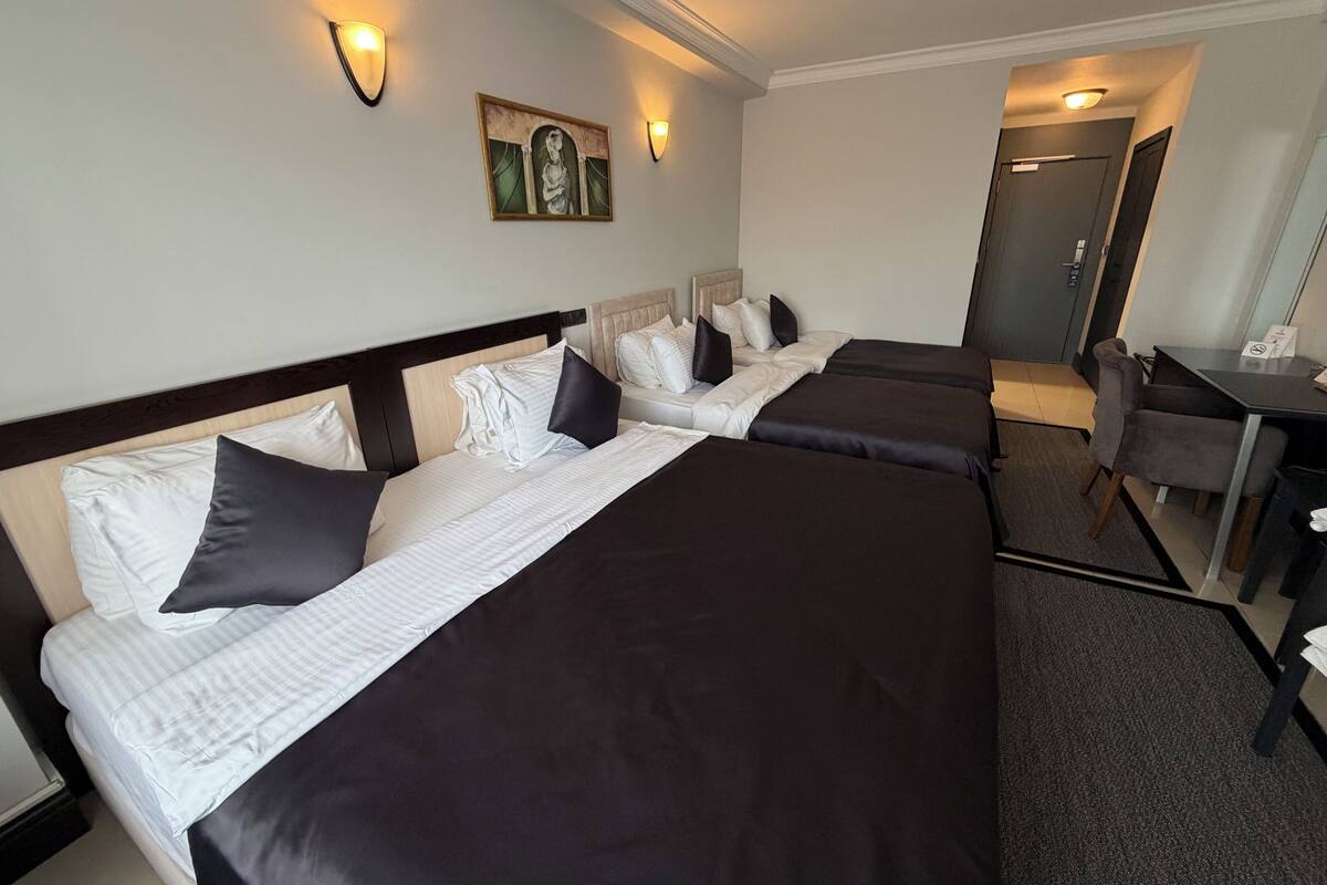 A hotel room with two beds, a desk, and a chair.