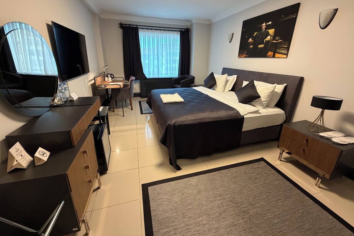 A hotel room with a bed, desk, chair, and a TV.