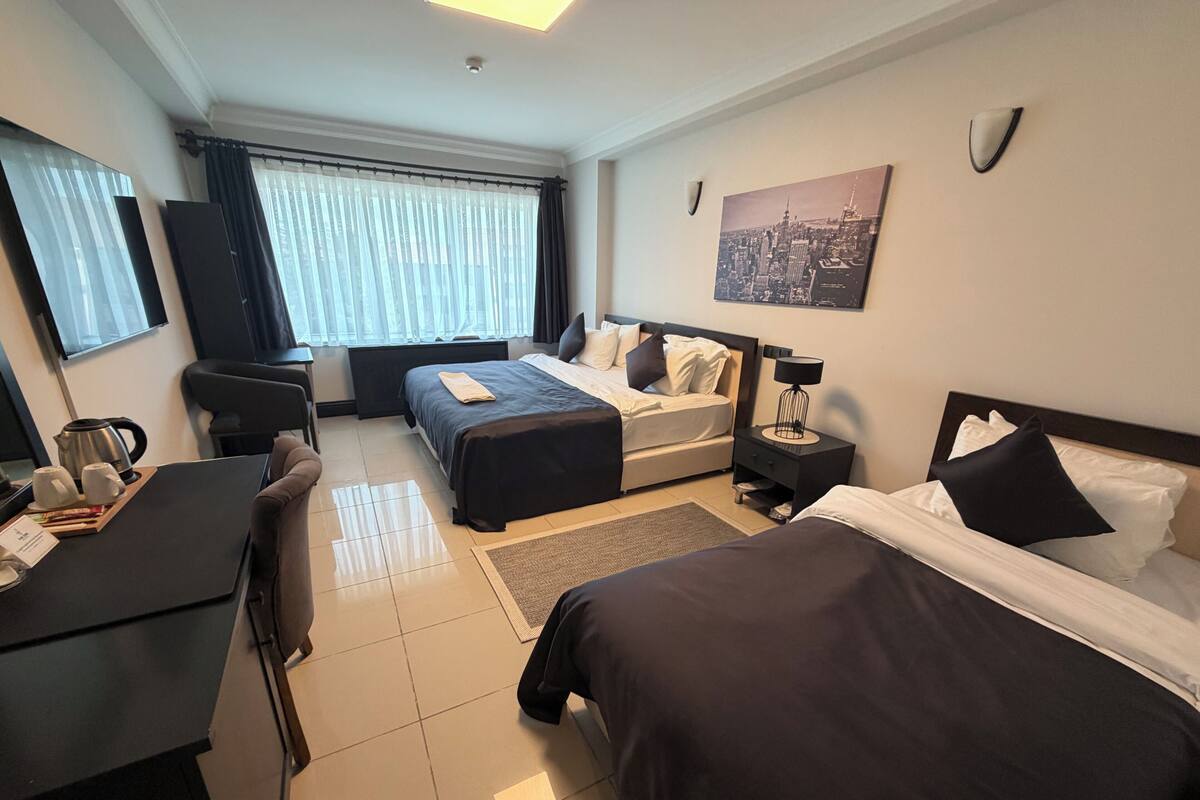 A hotel room with a bed, a sofa, a desk, and a coffee station.