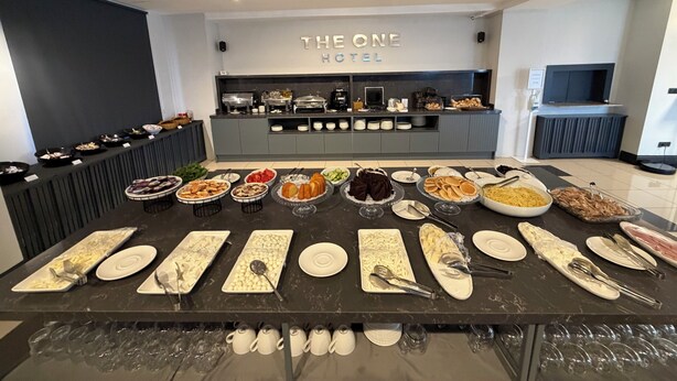 A buffet setup in a hotel with various food items and utensils laid out on a table. - THE ONE HOTEL (Kirsehir)