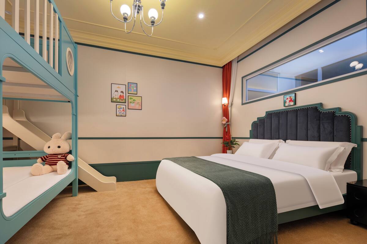 A bedroom with bunk beds, a bed, a window, and a chandelier.