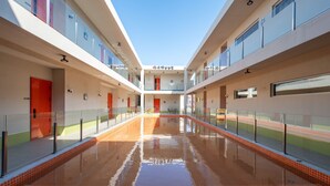 Un bâtiment moderne doté d’un atrium central, de rampes en verre et d’un sol carrelé.