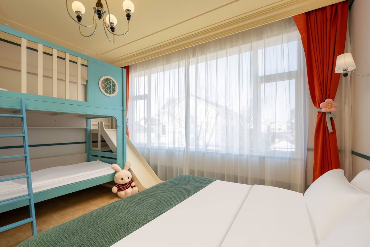 A child-friendly room with bunk beds, a small slide, and a large bed.