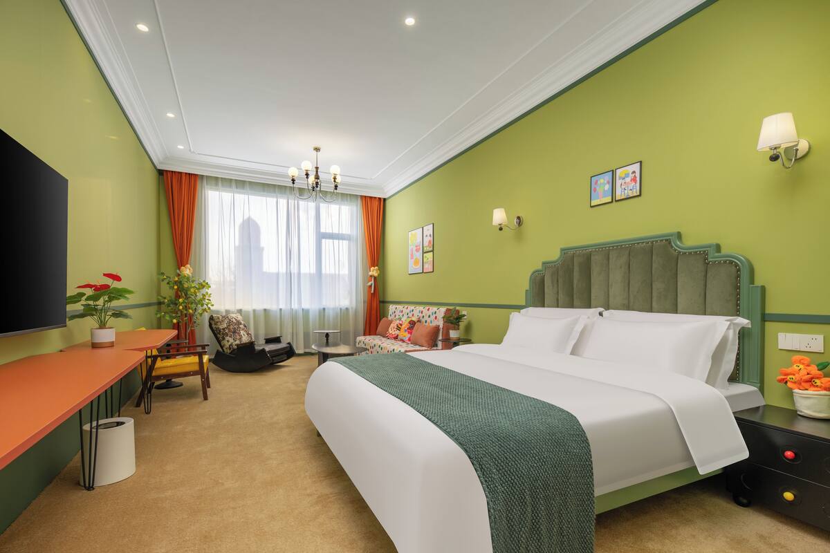 A hotel room with a bed, a desk, a chair, a television, and a window with curtains.