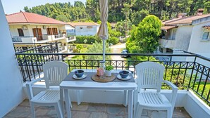 A balcony with a table and chairs, overlooking a residential area with houses and greenery.