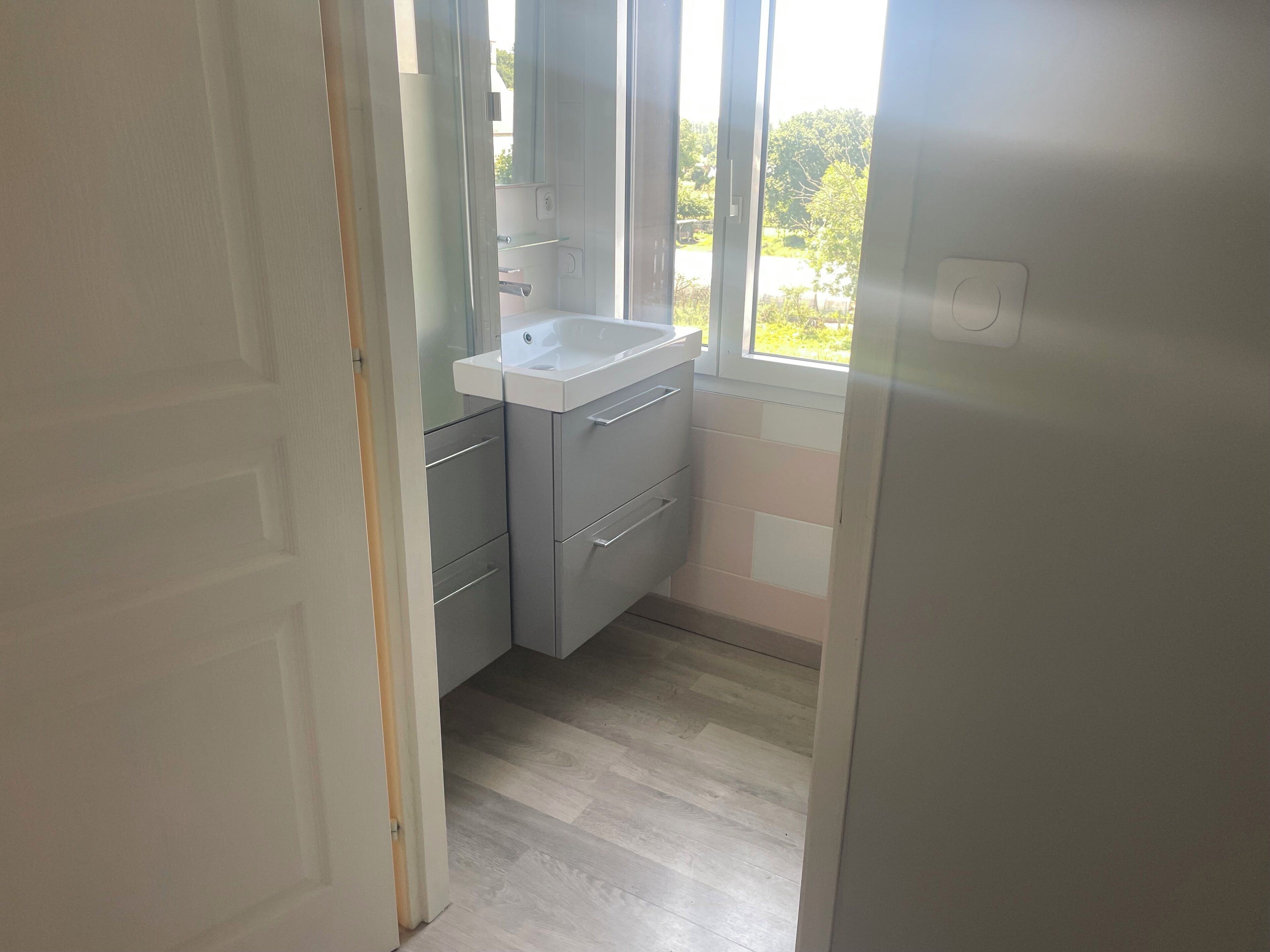 Un baño pequeño y moderno con lavamanos, armarios y ventana.