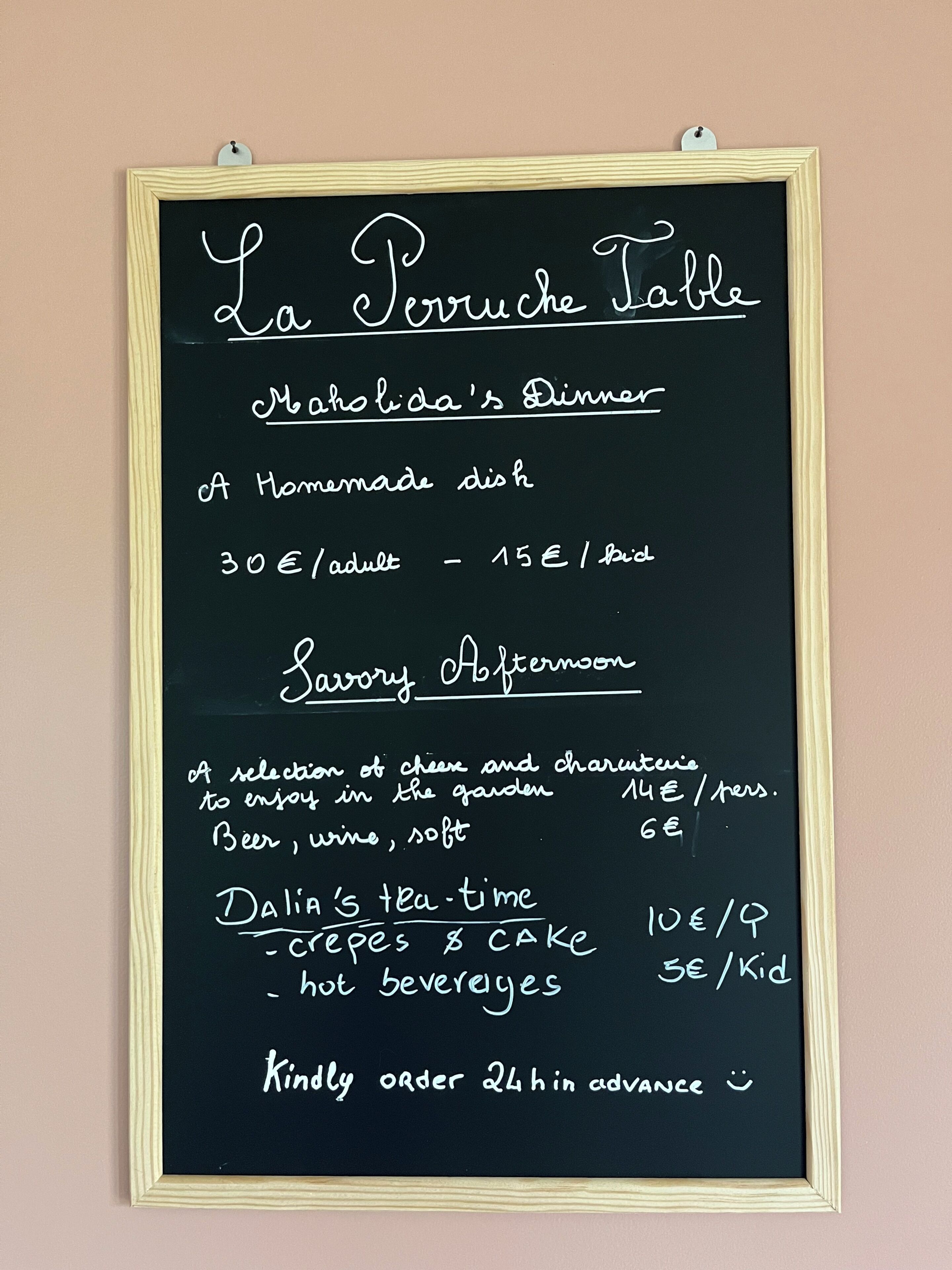 A chalkboard menu titled 'La Perruche Table' listing dinner, afternoon tea, and tea-time offerings with prices.
