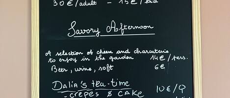 A chalkboard menu titled 'La Perruche Table' listing dinner, afternoon tea, and tea-time offerings with prices.