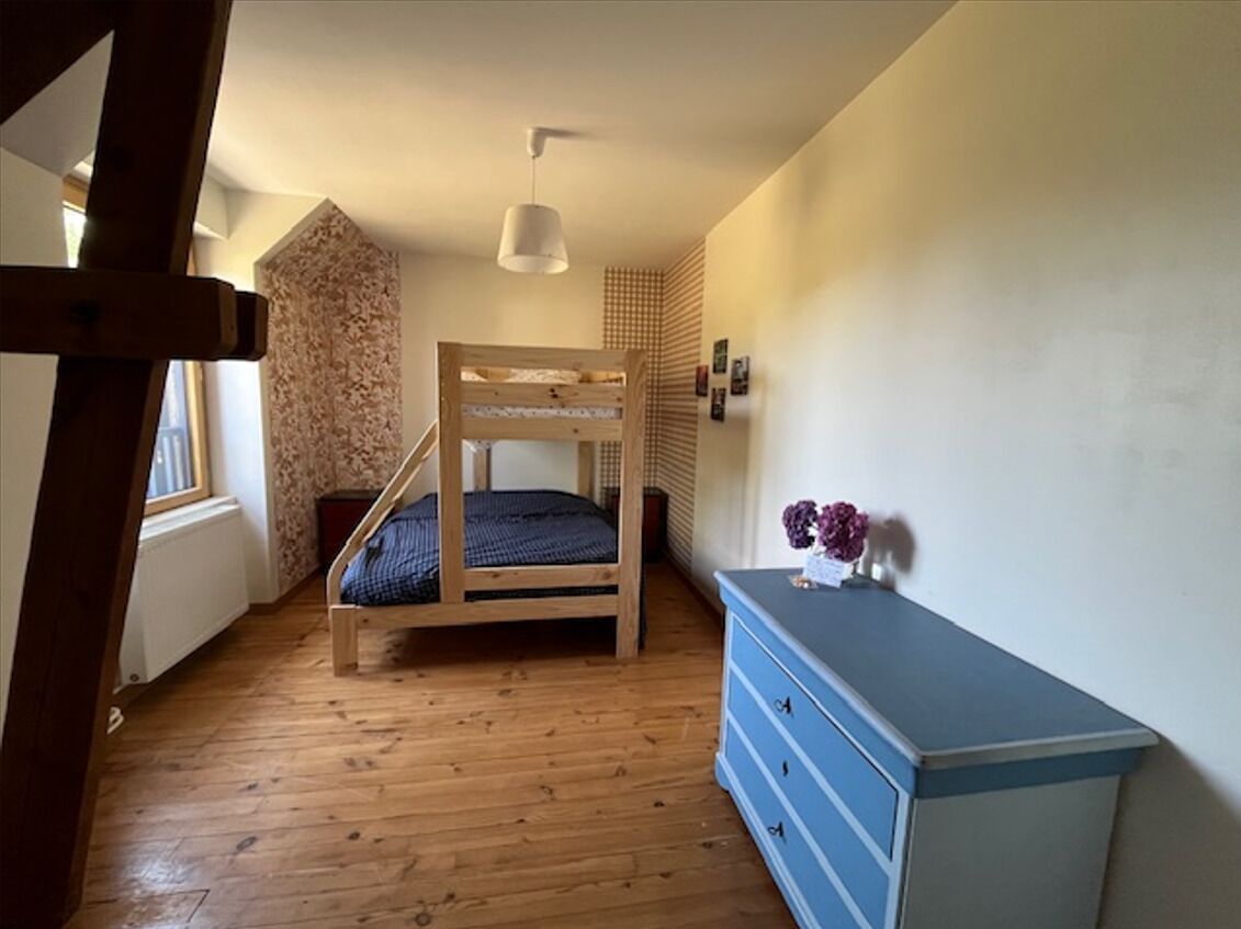 Ein Schlafzimmer mit Etagenbett, Holzboden, einem Schminktisch und einer Pendelleuchte.