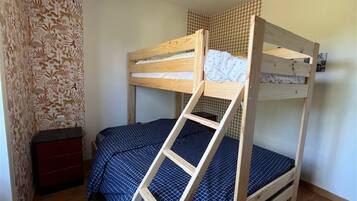 A bunk bed with a ladder, a small red dresser, and patterned wallpaper.