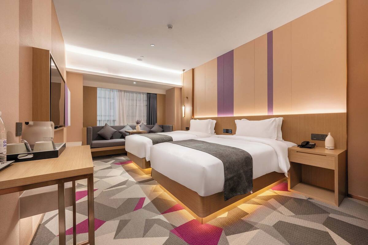 Habitació d'hotel moderna amb un llit gran, una taula de treball i un sofà.
