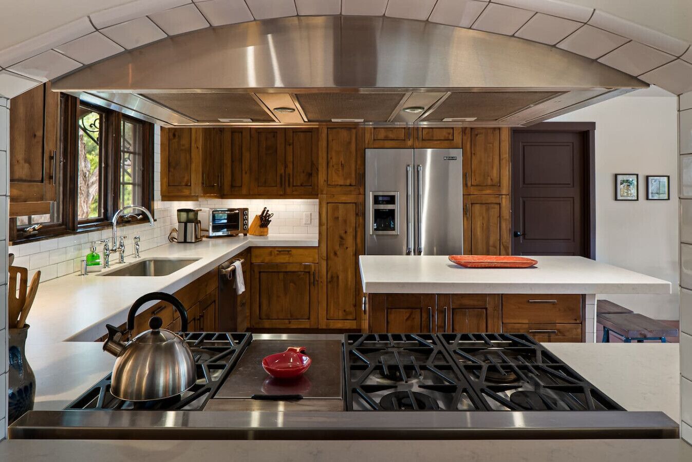 Une cuisine moderne avec des meubles en bois, des appareils électroménagers en acier inoxydable et une cuisinière à gaz.