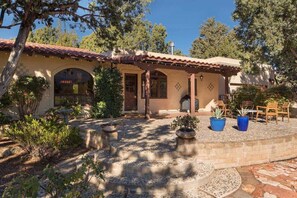 A Mediterranean-style building with a tiled roof, stone steps leading to a patio, and outdoor seating.