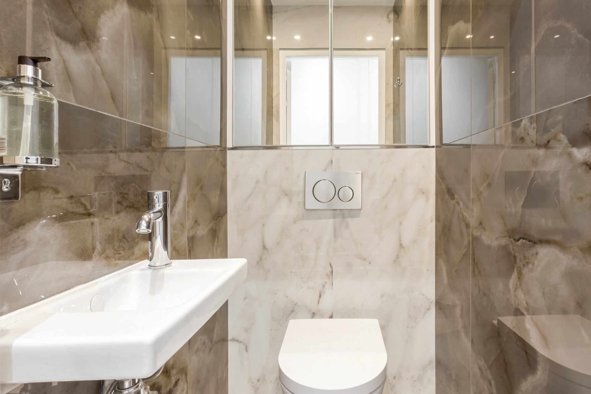 Une salle de bain moderne avec un lavabo blanc, des toilettes et une douche à parois de verre.