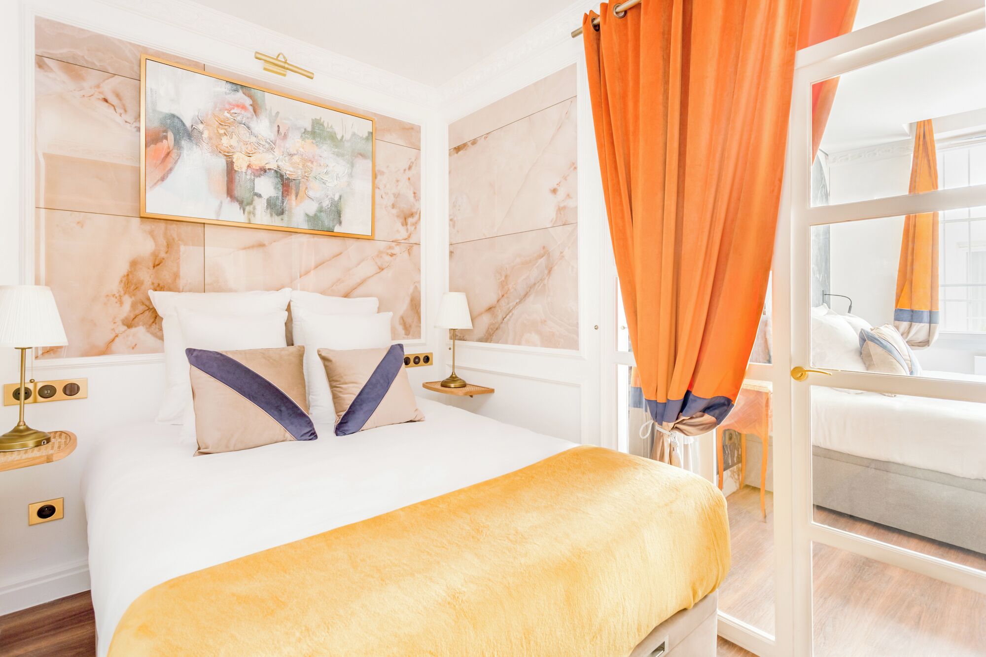 A hotel room with a bed, a nightstand, a lamp, and a painting on the wall.