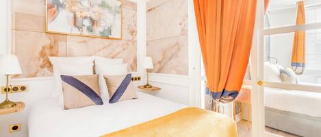 A hotel room with a bed, a nightstand, a lamp, and a painting on the wall.