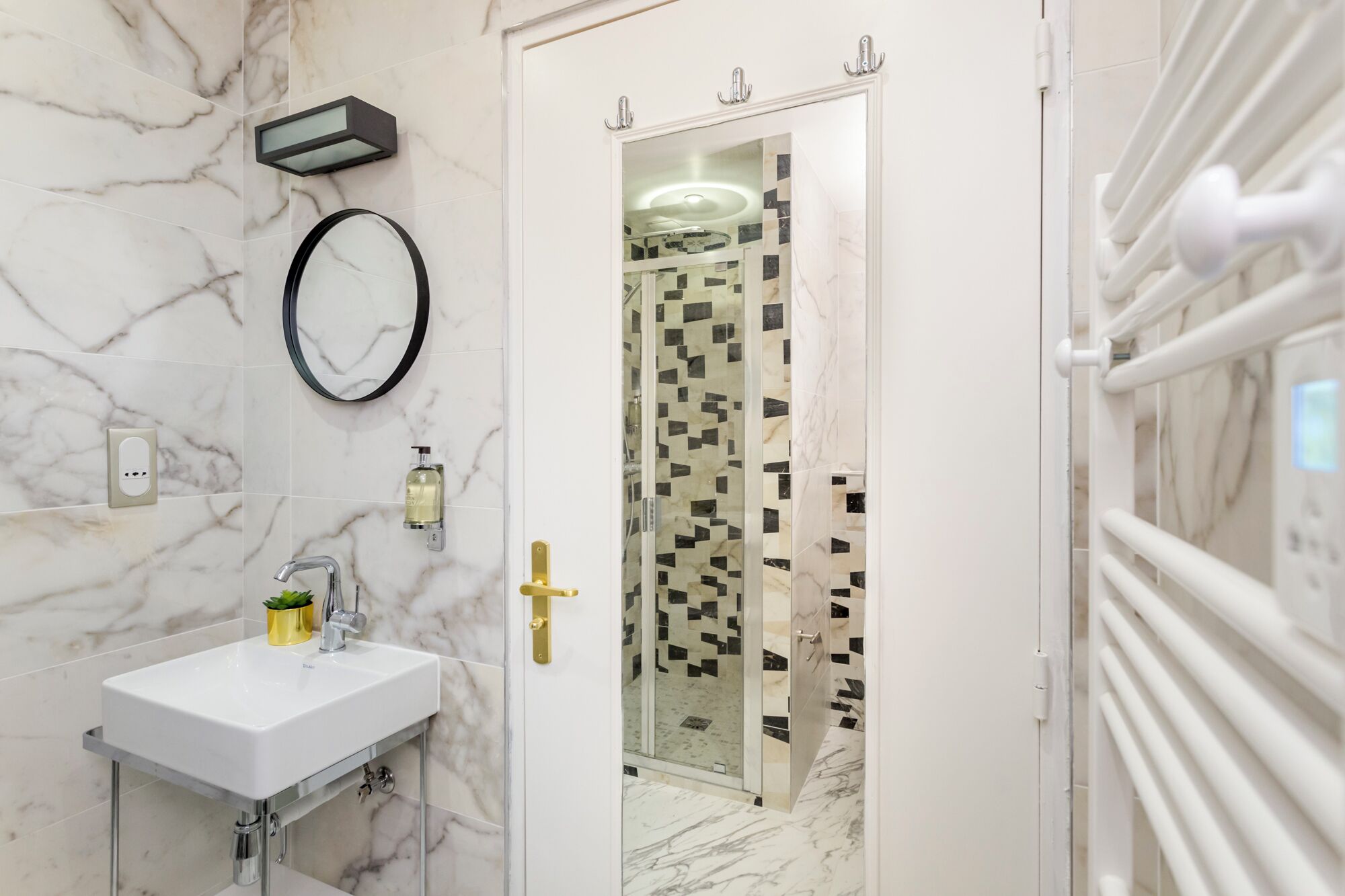 A bathroom with a white sink, a mirror, a glass shower enclosure, and a white towel rack.