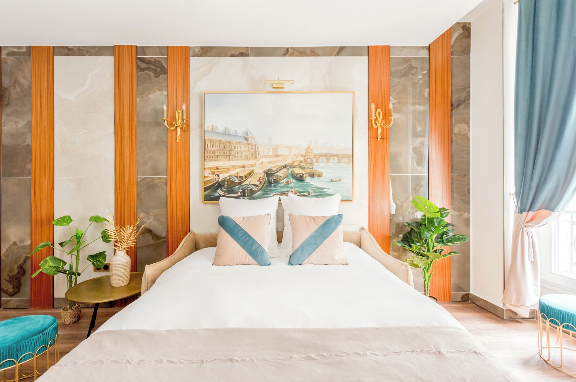 Een hotelkamer met een groot bed, een stadslandschap op doek, houten lambrisering en twee potplanten.
