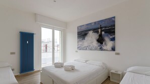 A hotel room with a large window, a bed, a nightstand, and a blue radiator. - Spacious flat with Balcony (Sestri Levante)