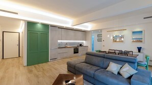 A modern living room with a grey sofa, a wooden coffee table, and a green door. - Spacious flat with Balcony (Sestri Levante)