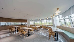 A modern dining area with wooden tables and chairs, large windows, and pendant lighting. - Tingxi Hotel Science Avenue Subway  (Hefei)
