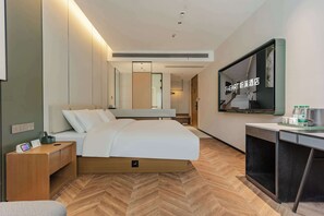 Una habitación de hotel moderna con una cama, mesita de noche, televisor y un escritorio con silla.