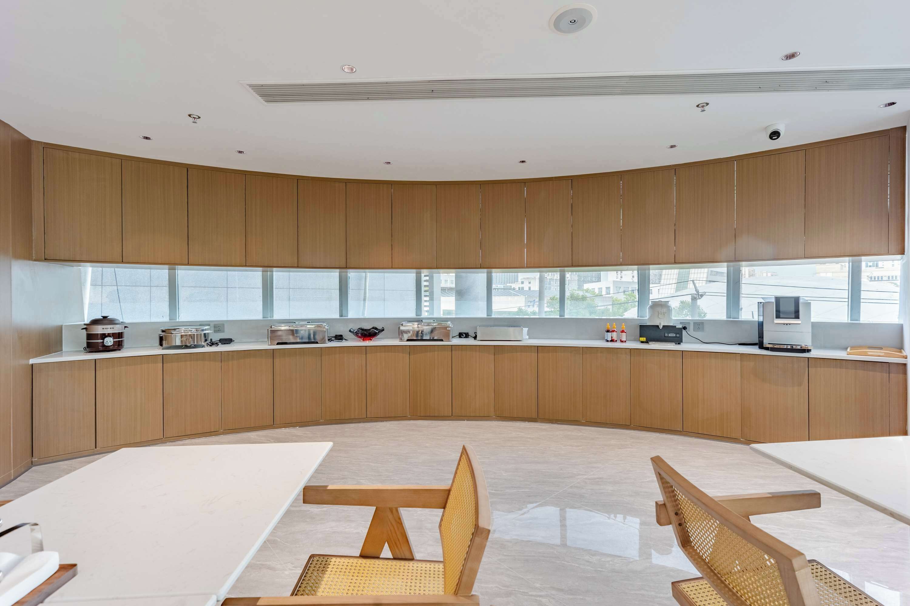 Een moderne keuken met houten kastjes, een lange aanrecht en een groot raam met uitzicht op de stad.